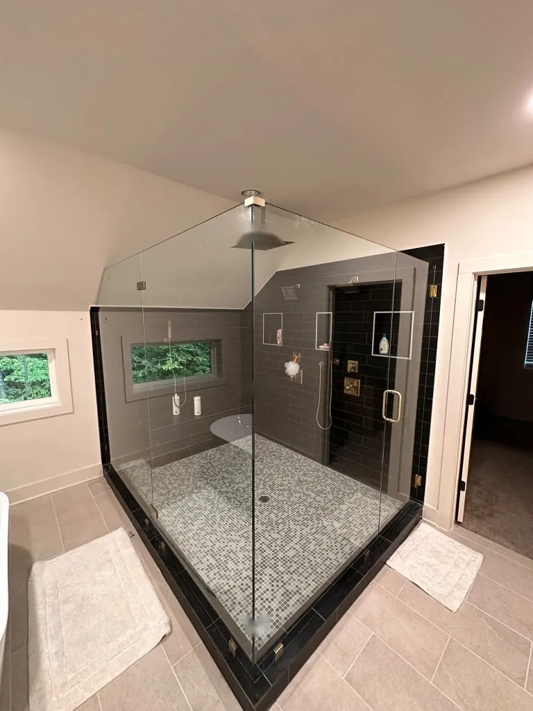 Ducha esquinera con azulejo hexagonal oscuro y ventana al jardin